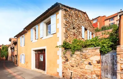 an old stone building with white windows on a street at Maison Vignes in Roussillon