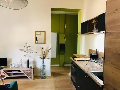 a kitchen with green walls and a vase of flowers at Chez Anna - Centre-ville - in LʼIsle-sur-la-Sorgue