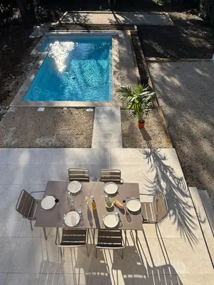 a table and chairs next to a swimming pool at Villa Mimosa in Venasque