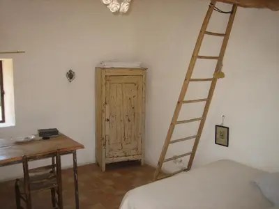 a room with a ladder next to a bed and a desk at Le cabanon in Vaugines