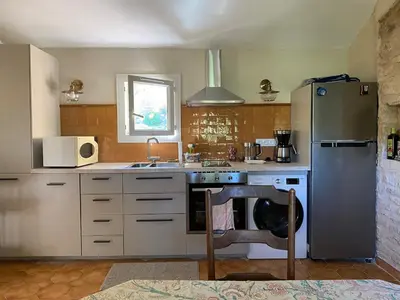 a kitchen with a stainless steel refrigerator and a sink at Bastidon, Petite bastide pour 2 avec bassin et jardin privé in Crillon-le-Brave