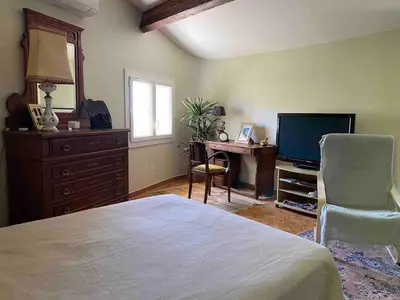 a bedroom with a bed and a desk and a television at Bastidon, Petite bastide pour 2 avec bassin et jardin privé in Crillon-le-Brave