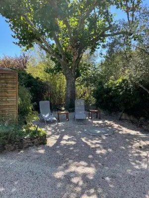 two chairs and a table under a tree at Charmant Mazet en campagne provencale in Châteaurenard