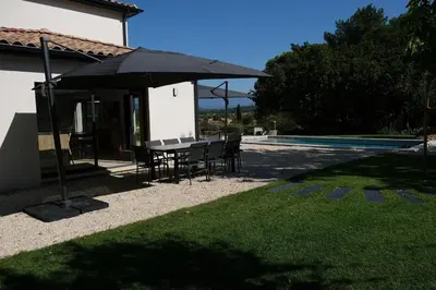 a table and chairs under an umbrella next to a pool at Villa with heated pool and Ventoux View in Pernes in Pernes-les-Fontaines