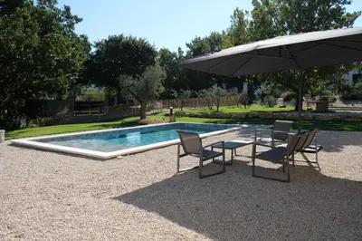a table and chairs with an umbrella next to a swimming pool at Villa with heated pool and Ventoux View in Pernes in Pernes-les-Fontaines