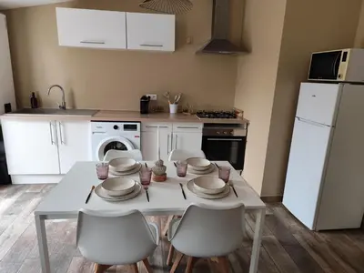 a kitchen with a white table and chairs and a white refrigerator at Petite maison de charme in LʼIsle-sur-la-Sorgue