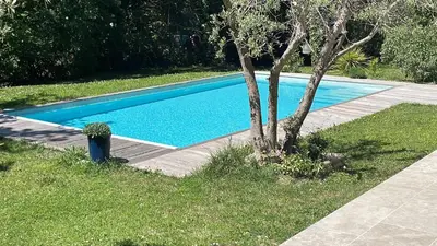 a blue swimming pool with a tree next to it at Studio indépendant dans propriété campagne Aixoise terrasse et piscine période estivale in Aix-en-Provence