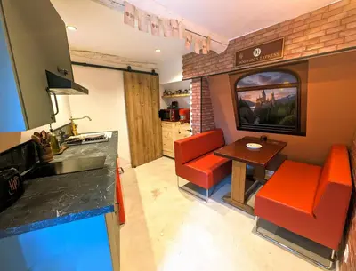 a kitchen with orange chairs and a table in a room at Le Repaire du Sorcier in Caumont-sur-Durance