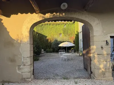 an archway with a table and an umbrella in a courtyard at Mas Provençal avec piscine à Gordes in Gordes