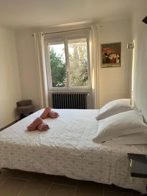 a bedroom with a large white bed with a window at La casemate in LʼIsle-sur-la-Sorgue