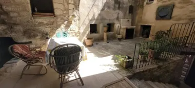 a patio with a table and chairs in a stone building at Magnifique demeure de caractère au cœur de Lacoste in Lacoste