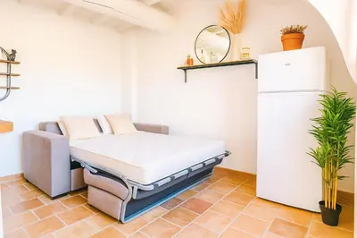 a bed in a room with a refrigerator at Le Nily Provence, T2 cosy rénové avec Clim, Extérieur et Parking in Sainte-Tulle