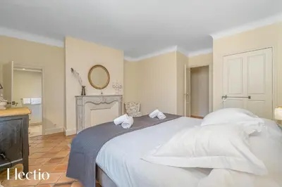 a bedroom with a large white bed and a fireplace at Château Constantin in Cadenet