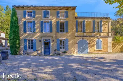 an old house with blue windows and a tree at Château Constantin in Cadenet