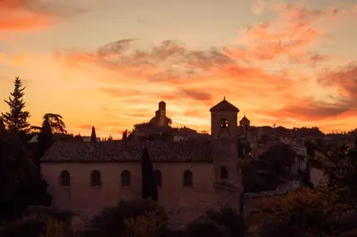 an old building with a sunset in the background at Hôtel de La Fontaine in Lourmarin