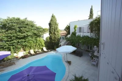 a swimming pool with an umbrella next to a building at Maison Pertuis Provence in Pertuis