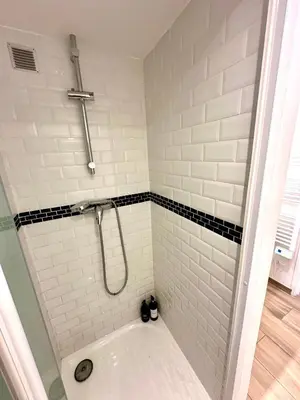 a bathroom with a tub and a shower with white tiles at Le Bleu Salonais - Centre ville in Salon-de-Provence