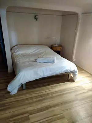 a bed with white sheets on it in a bedroom at Chambre Centre Aix Salle de Bain privée in Aix-en-Provence