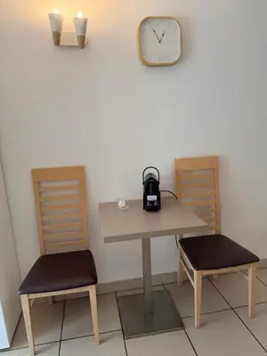 a table and two chairs and a clock on a wall at Le Clos d'AIX studio 205 in Aix-en-Provence
