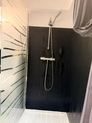 a shower in a bathroom with a black tiled wall at Le Clos d'AIX studio 205 in Aix-en-Provence