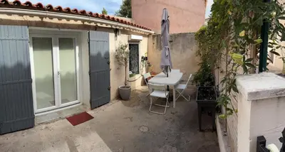 a small patio with a table and an umbrella at L'olivade in La Fare-les-Oliviers