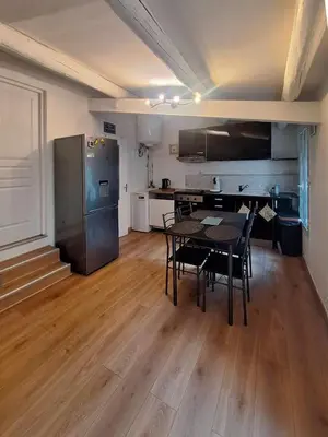 a kitchen and dining room with a table and a refrigerator at L'olivade in La Fare-les-Oliviers
