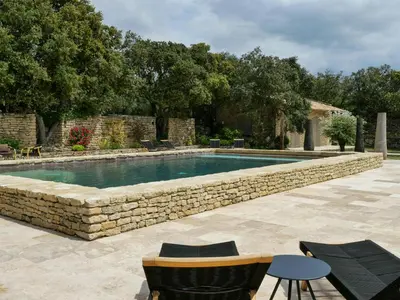 a swimming pool with a stone wall around it at Stunning Stone House With Pool Near Gordes in Gordes
