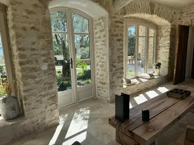 a living room with a tv and a large window at Stunning Stone House With Pool Near Gordes in Gordes