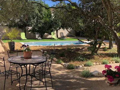 a table and chairs in a yard with a pool at La Parenthèse Montilienne à 10mn d'Avignon in Monteux