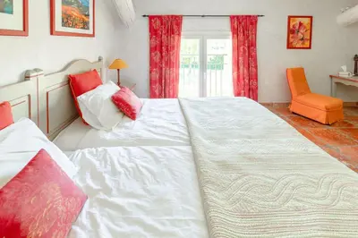 a bedroom with a large white bed and an orange chair at Mas, Padel privé, tennis privé, piscine 22m , Alpilles Provence in Orgon