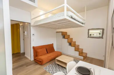 an orange couch in a living room with a staircase at Le Zola - Studio premium hypercentre - Wifi - Climatisation in Aix-en-Provence