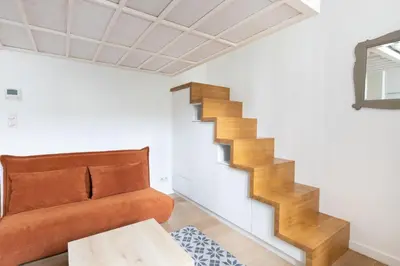 a living room with a couch and a staircase at Le Zola - Studio premium hypercentre - Wifi - Climatisation in Aix-en-Provence