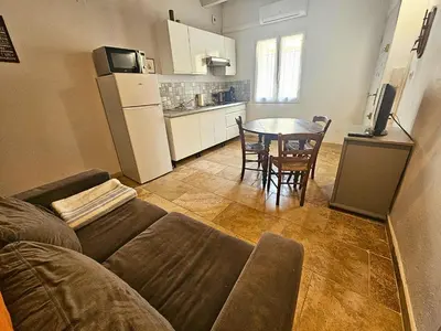a living room with a couch and a table and a kitchen at Au coeur de la Venise Povençale in LʼIsle-sur-la-Sorgue