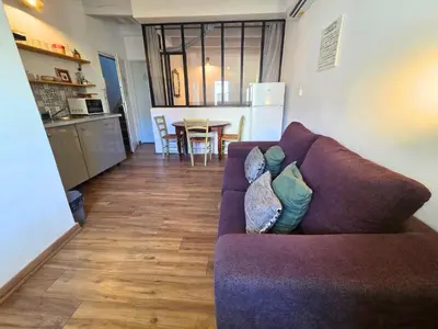 a living room with a purple couch and a kitchen at Magnifique appartement au cœur de la Venise Provençale in LʼIsle-sur-la-Sorgue