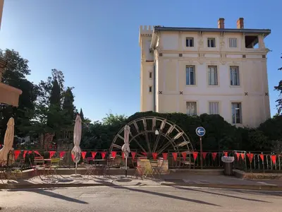 a building with tables and umbrellas in front of a building at Magnifique appartement au cœur de la Venise Provençale in LʼIsle-sur-la-Sorgue