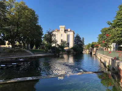 a view of a river with a building in the background at Magnifique appartement au cœur de la Venise Provençale in LʼIsle-sur-la-Sorgue