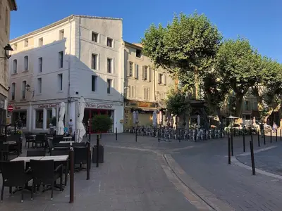 an empty street with tables and chairs and buildings at Magnifique appartement au cœur de la Venise Provençale in LʼIsle-sur-la-Sorgue