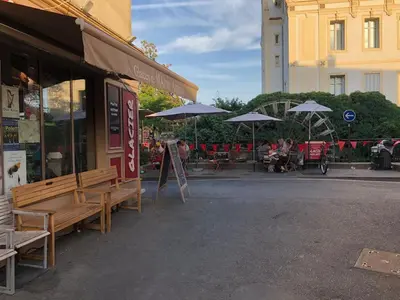 a cafe with benches and umbrellas on a street at Magnifique appartement au cœur de la Venise Provençale in LʼIsle-sur-la-Sorgue