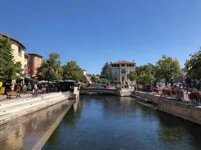 a river in a city with a bridge at Superbe appartement dans la Venise Provençale in LʼIsle-sur-la-Sorgue
