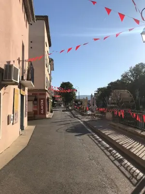 an empty street next to a train station with flags at Superbe appartement dans la Venise Provençale in LʼIsle-sur-la-Sorgue