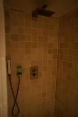 a shower with a hose in a tiled bathroom at La Bergerie de Saignon in Saignon