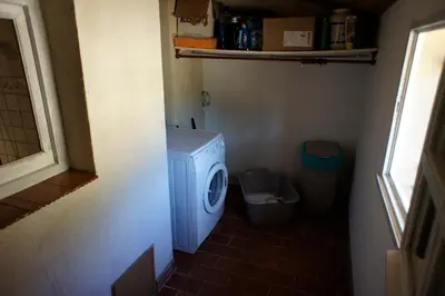 a small bathroom with a washing machine and a trash can at La Bergerie de Saignon in Saignon