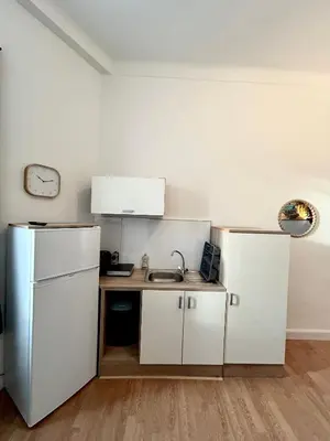 a kitchen with white cabinets and a sink and a refrigerator at Studio lumineux au cœur du Luberon Parking gratui in Cavaillon