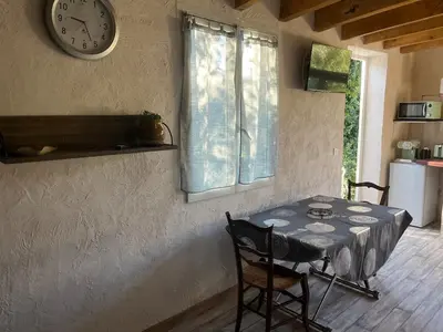 a dining room with a table and a clock on the wall at studio à la campagne avec piscine in Peyrolles-en-Provence