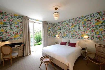 a bedroom with a large bed with colorful wallpaper at Grand Hôtel Henri - Teritoria in LʼIsle-sur-la-Sorgue