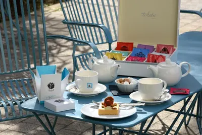 a blue table with tea cups and desserts on it at Grand Hôtel Henri - Teritoria in LʼIsle-sur-la-Sorgue