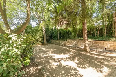 a garden with trees and a stone wall at Le Casanelle in Aix-en-Provence