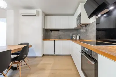 a kitchen with white cabinets and a wooden table at Le Casanelle in Aix-en-Provence