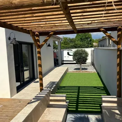 a backyard with a wooden pergola and a lawn at Terres de Durance in Charleval