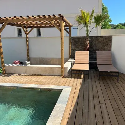 a deck with benches and a swimming pool and a pergola at Terres de Durance in Charleval